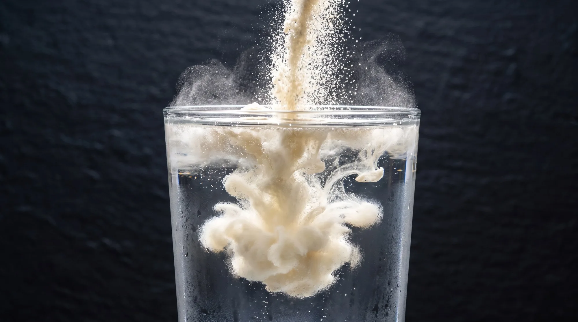 Protein powder pouring into a glass of water